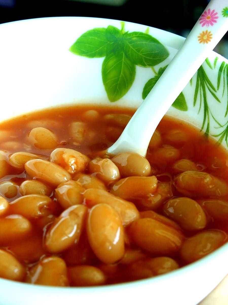 Baked beans in tomato sauce in a white bowl.