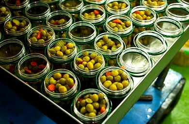 Glass jars filled with olives and vegetables on a production line